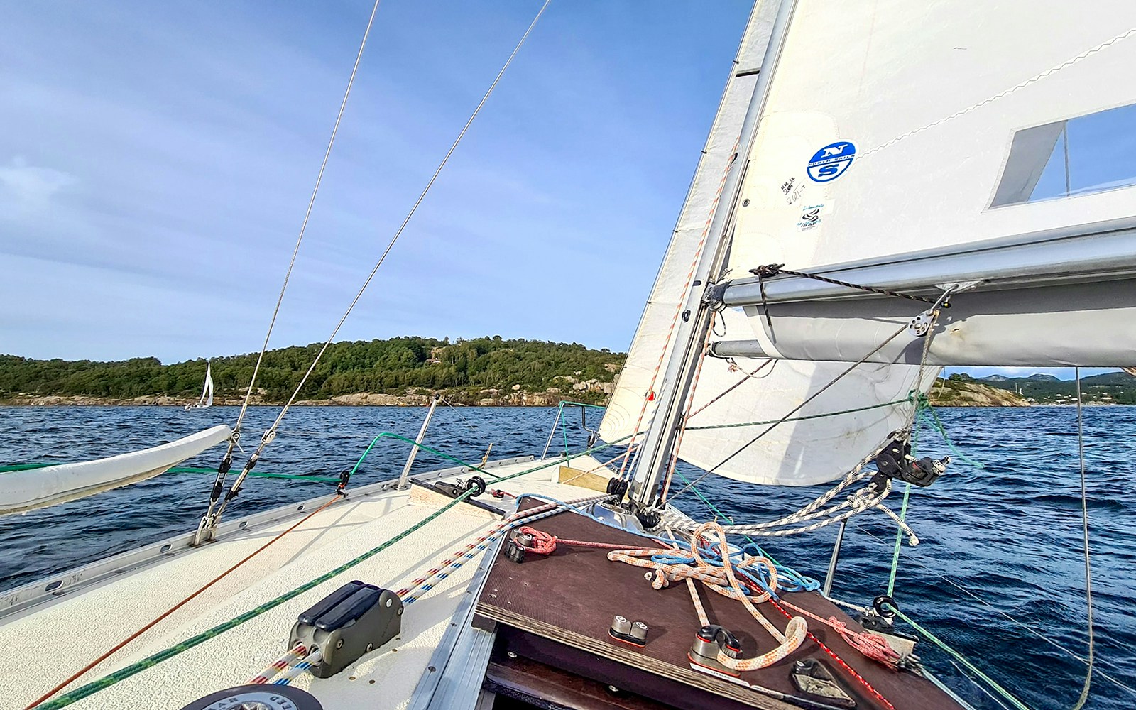 Sailing through Stavanger Fjord with a view of a lush green island.