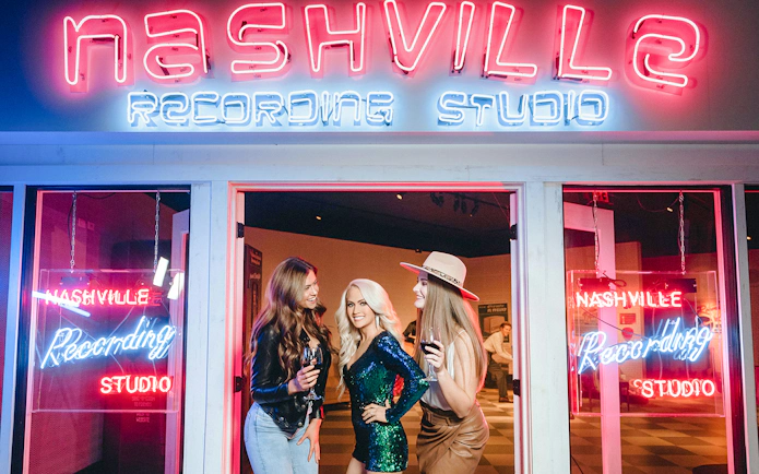 Guests enjoying wax figures at Madame Tussauds Nashville recording studio exhibit.
