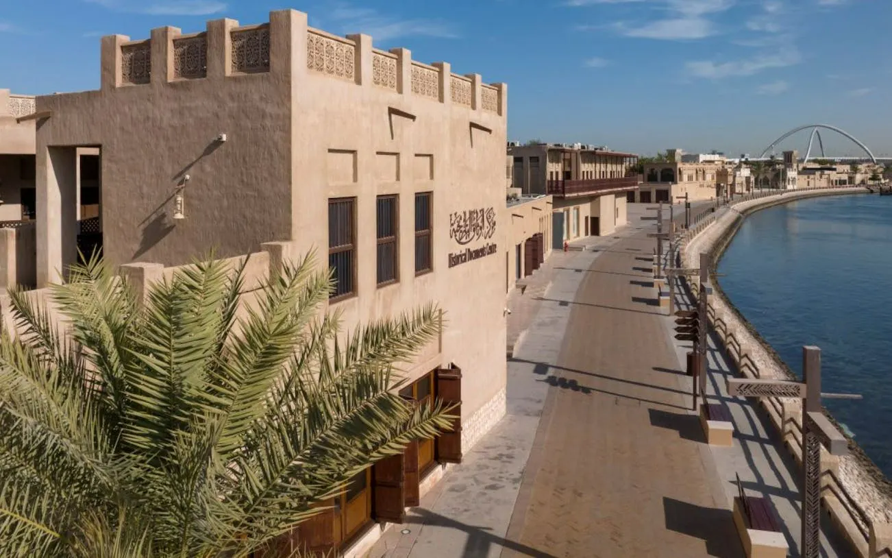 Dubai heritage district with traditional architecture along a waterfront promenade.