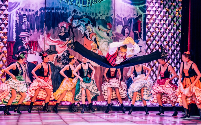 Dancers performing at Cabaret La Nouvelle Eve in Paris with vibrant costumes.