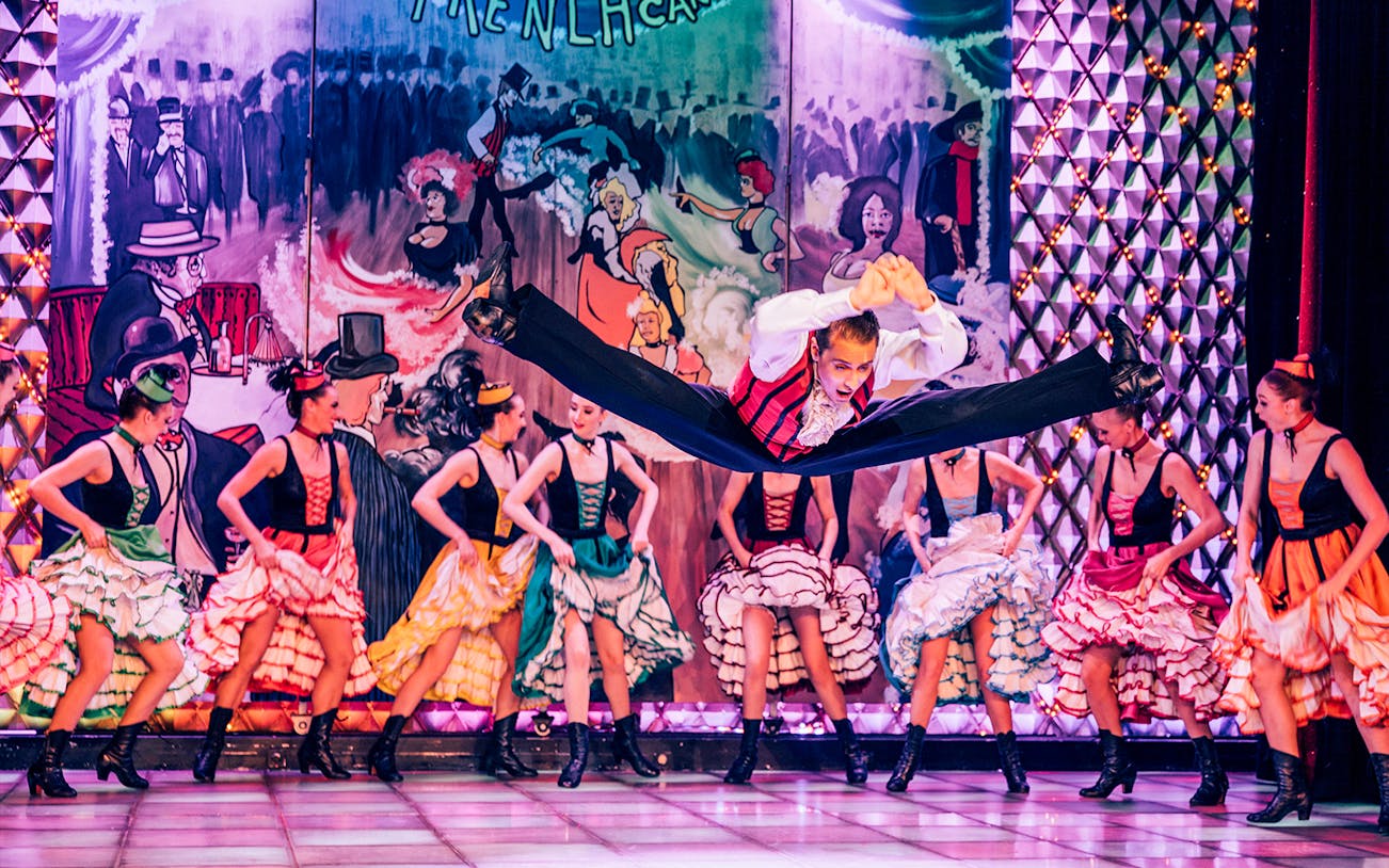 Dancers performing at Cabaret La Nouvelle Eve in Paris with vibrant costumes.