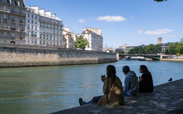 Participants relax by the Seine River in Paris during a guided tour.