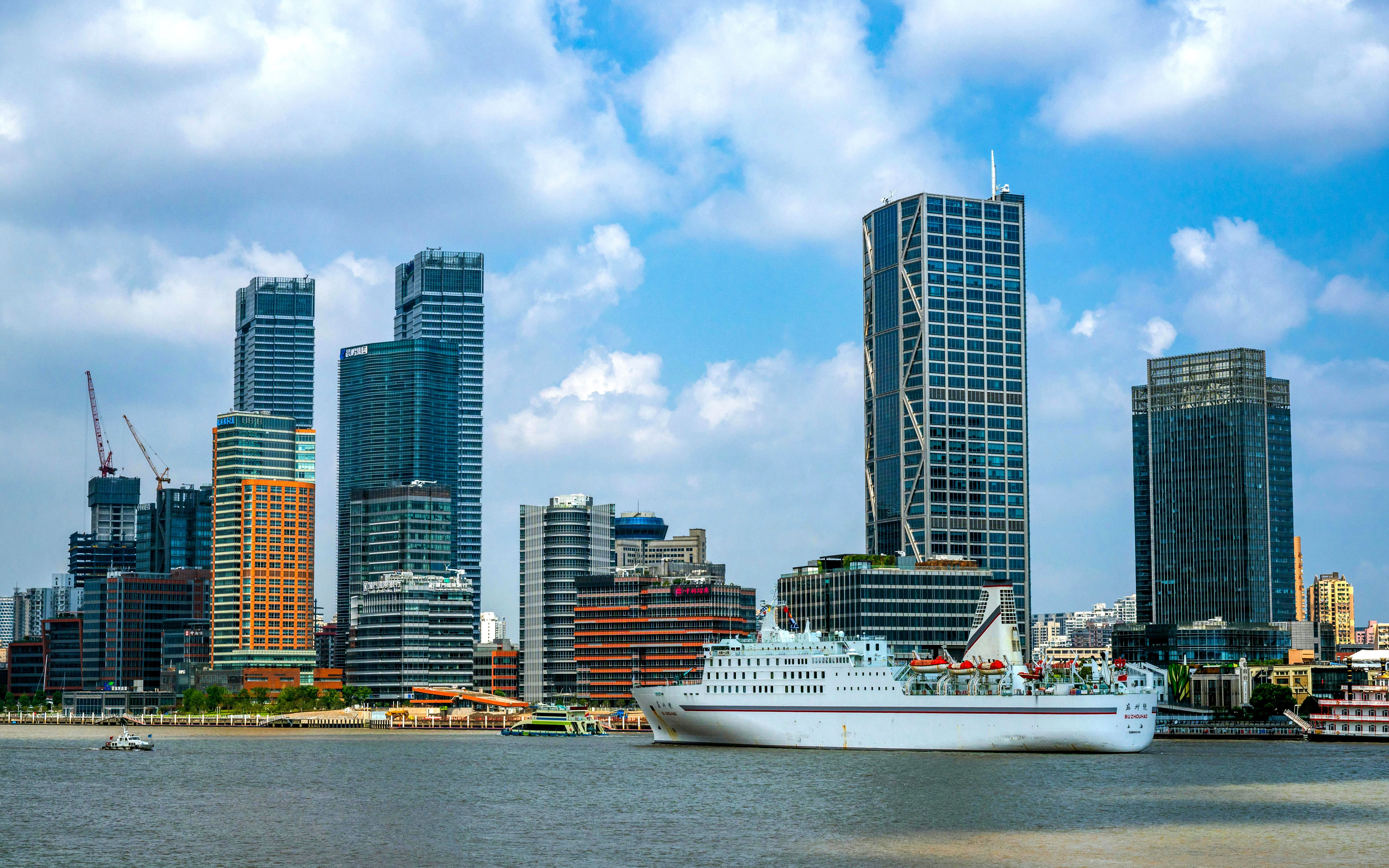 Cruise ship on the Huangpu River with North Bund Waterfront skyscrapers in Shanghai.