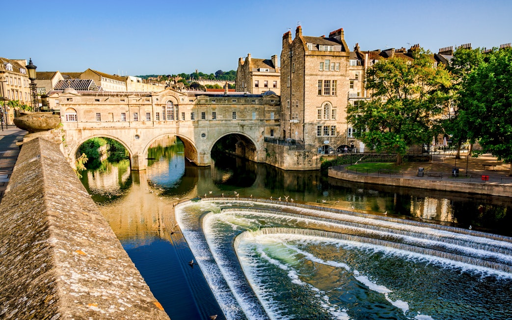 Pulteney Bridge spanning the River Avon in Bath, England, with cascading weir in foreground.