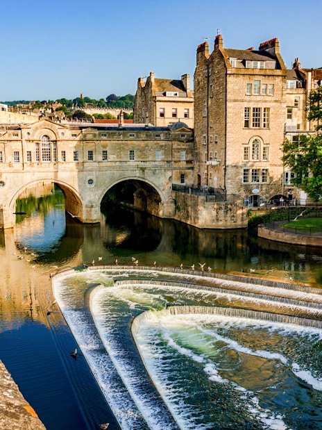 Pulteney Bridge spanning the River Avon in Bath, England, with cascading weir in foreground.