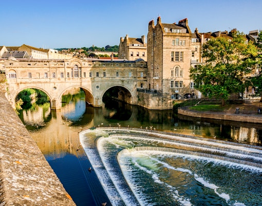 Pulteney Bridge spanning the River Avon in Bath, England, with cascading weir in foreground.