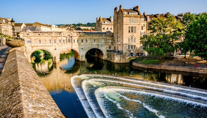 Pulteney Bridge spanning the River Avon in Bath, England, with cascading weir in foreground.