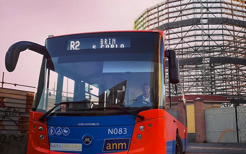 Naples city bus near construction site, offering round-trip tickets to/from Naples Airport.