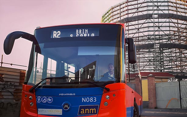 Naples city bus near construction site, offering round-trip tickets to/from Naples Airport.