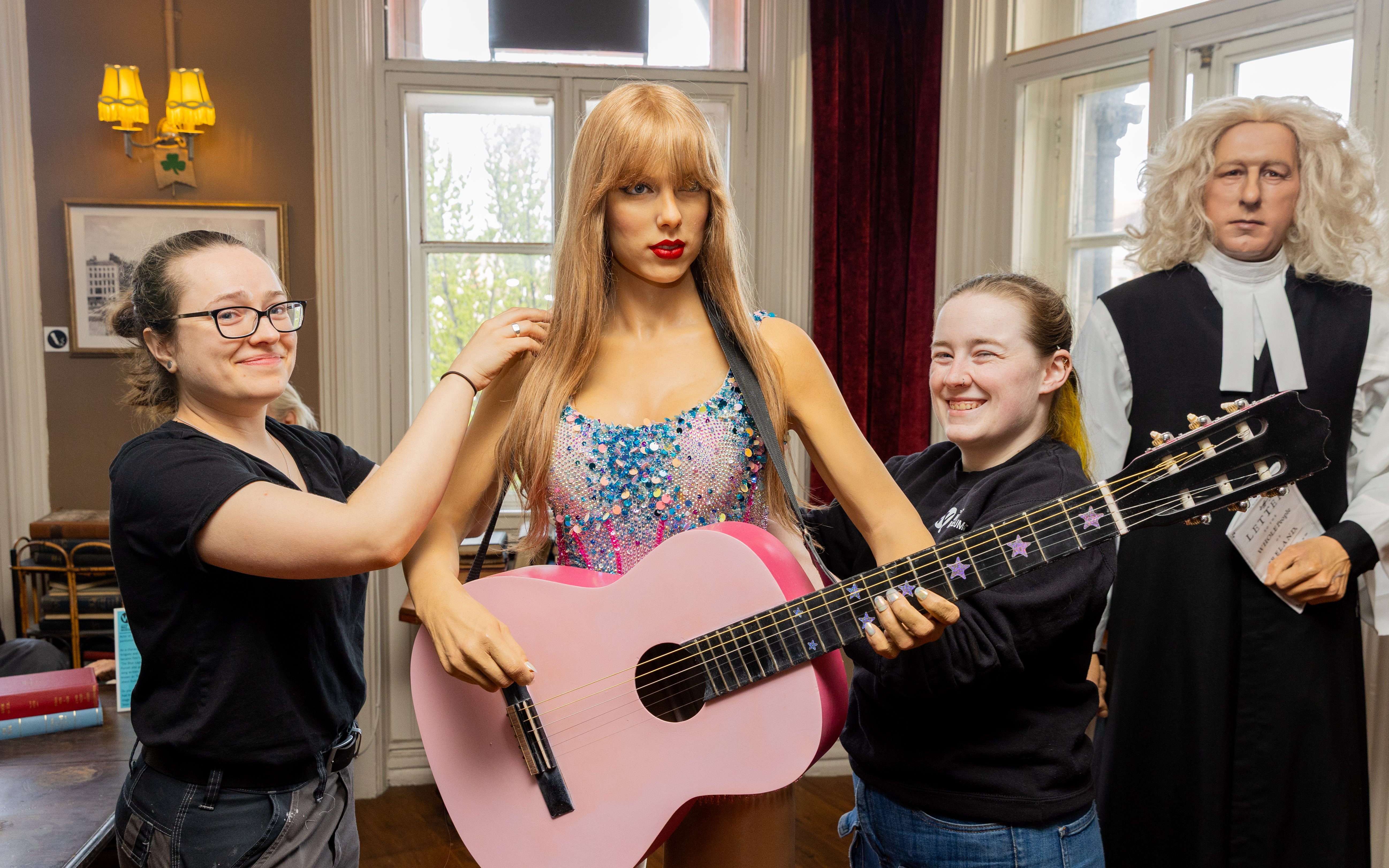 Wax figures at Dublin National Wax Museum with visitors adjusting a guitar.