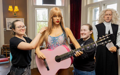 Wax figures at Dublin National Wax Museum with visitors adjusting a guitar.