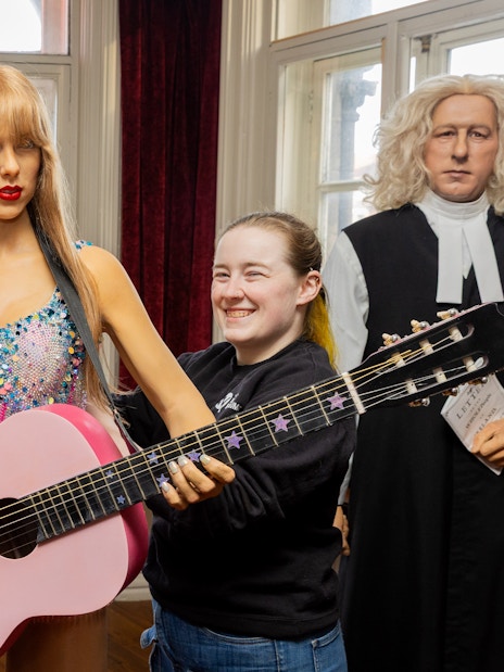 Wax figures at Dublin National Wax Museum with visitors adjusting a guitar.