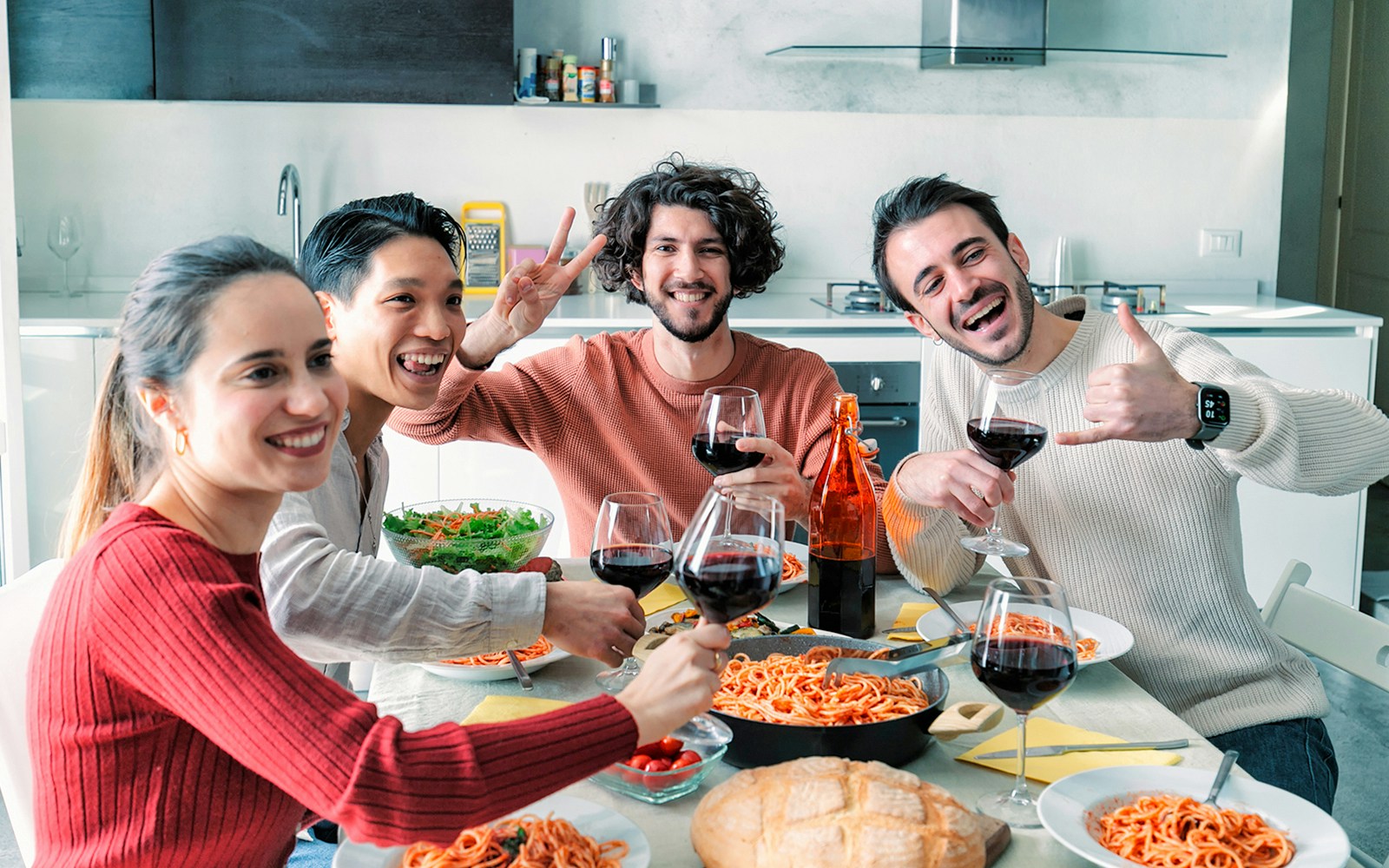 Friends enjoying pasta and wine at a home lunch party.
