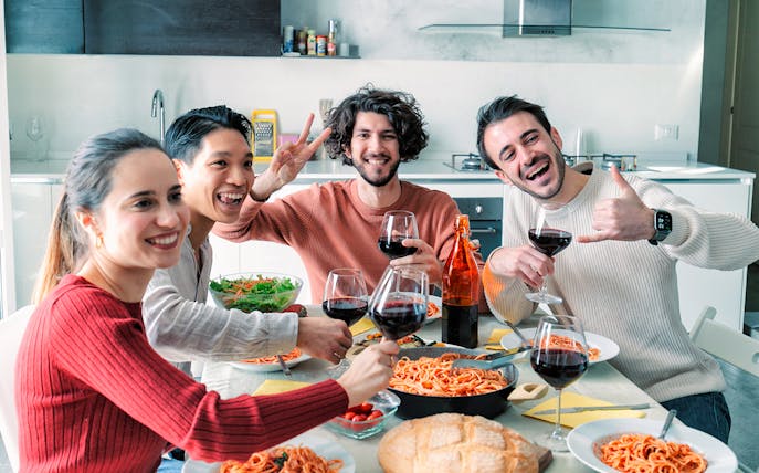 Friends enjoying pasta and wine at a home lunch party.