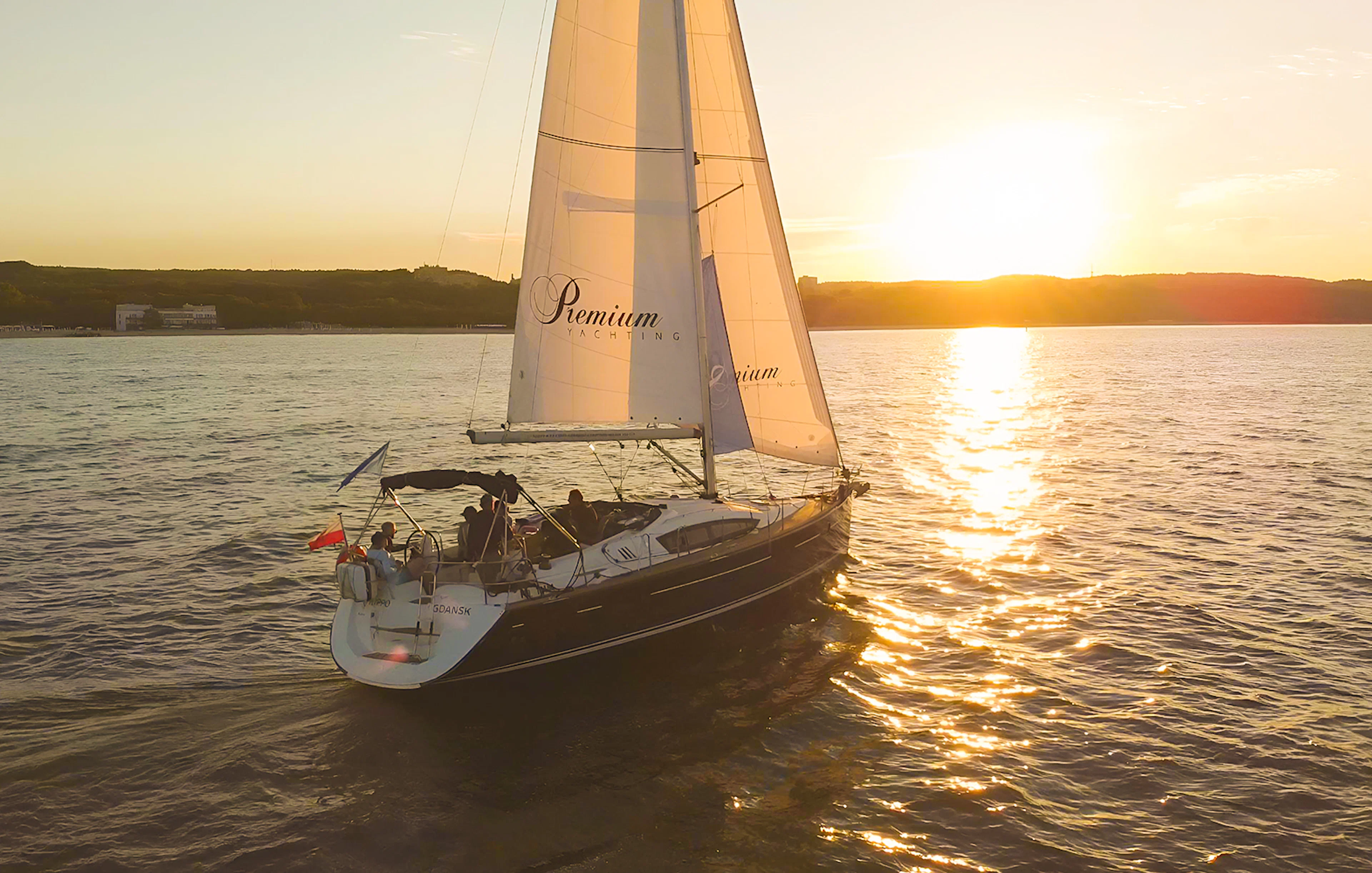 Sailboat on sunset cruise from Sopot Pier with sun setting over the water.