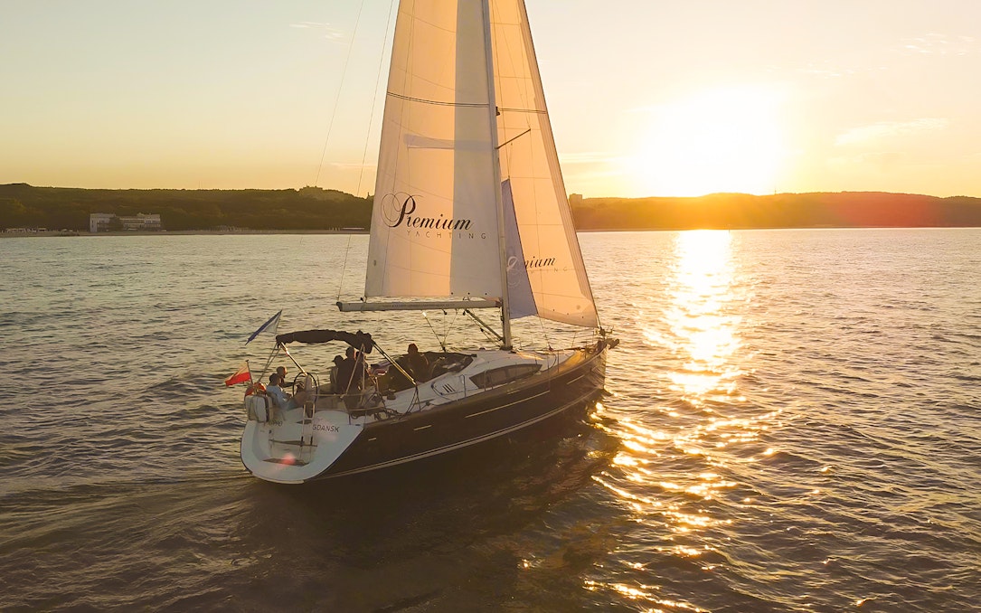 Sailboat on sunset cruise from Sopot Pier with sun setting over the water.