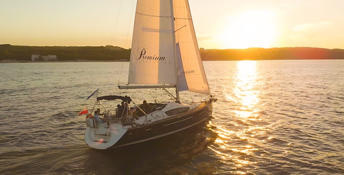 Sailboat on sunset cruise from Sopot Pier with sun setting over the water.