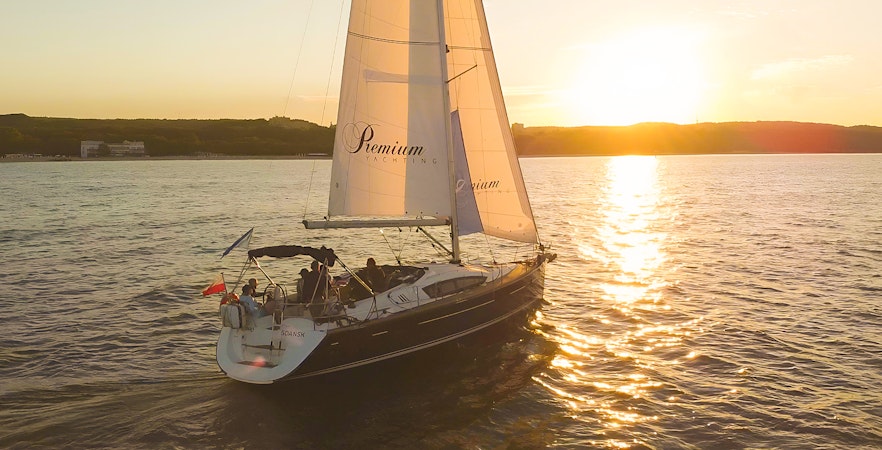 Sailboat on sunset cruise from Sopot Pier with sun setting over the water.