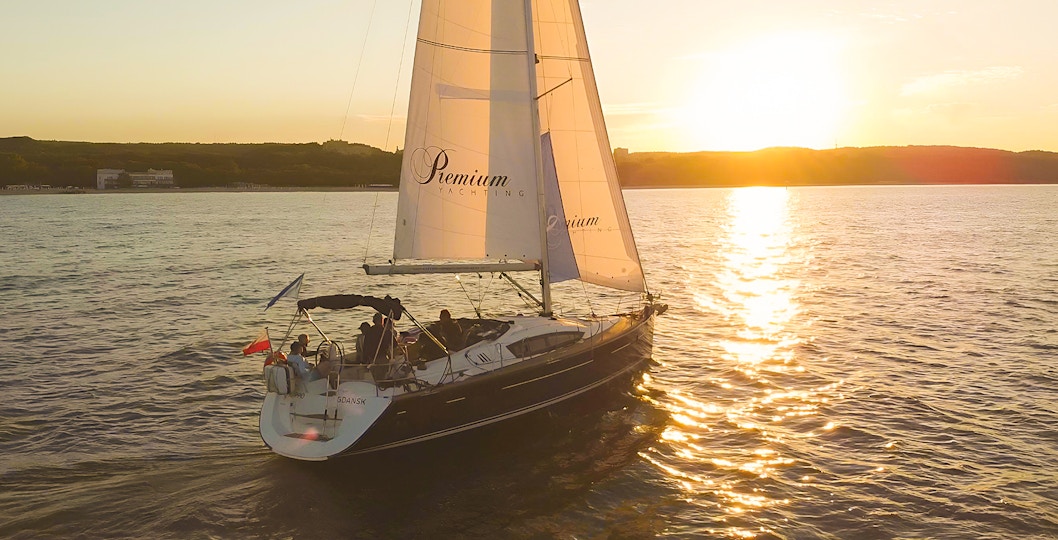 Sailboat on sunset cruise from Sopot Pier with sun setting over the water.