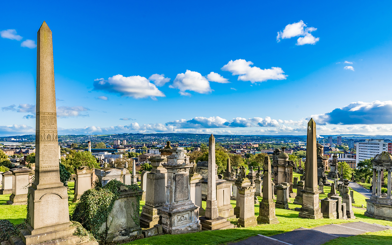 Victorian tombstones and obelisks at Glasgow Necropolis, overlooking the cityscape of Glasgow, Scotland.