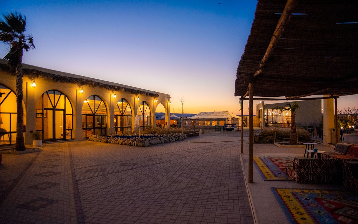 Courtyard at Al Majles Resort during sunset with lit arches and seating area.