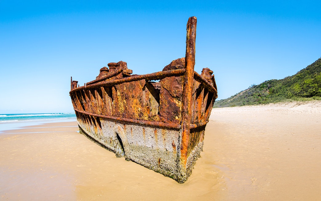 Maheno Shipwreck on sandy beach, Fraser Island, K'gari, under clear blue sky.