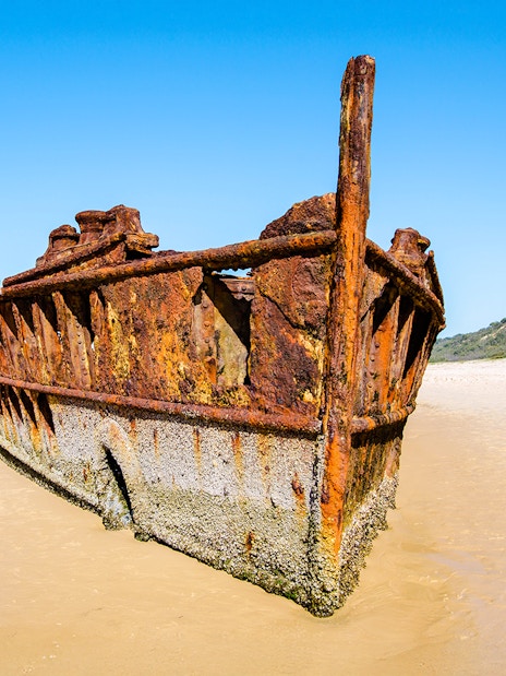Maheno Shipwreck on sandy beach, Fraser Island, K'gari, under clear blue sky.