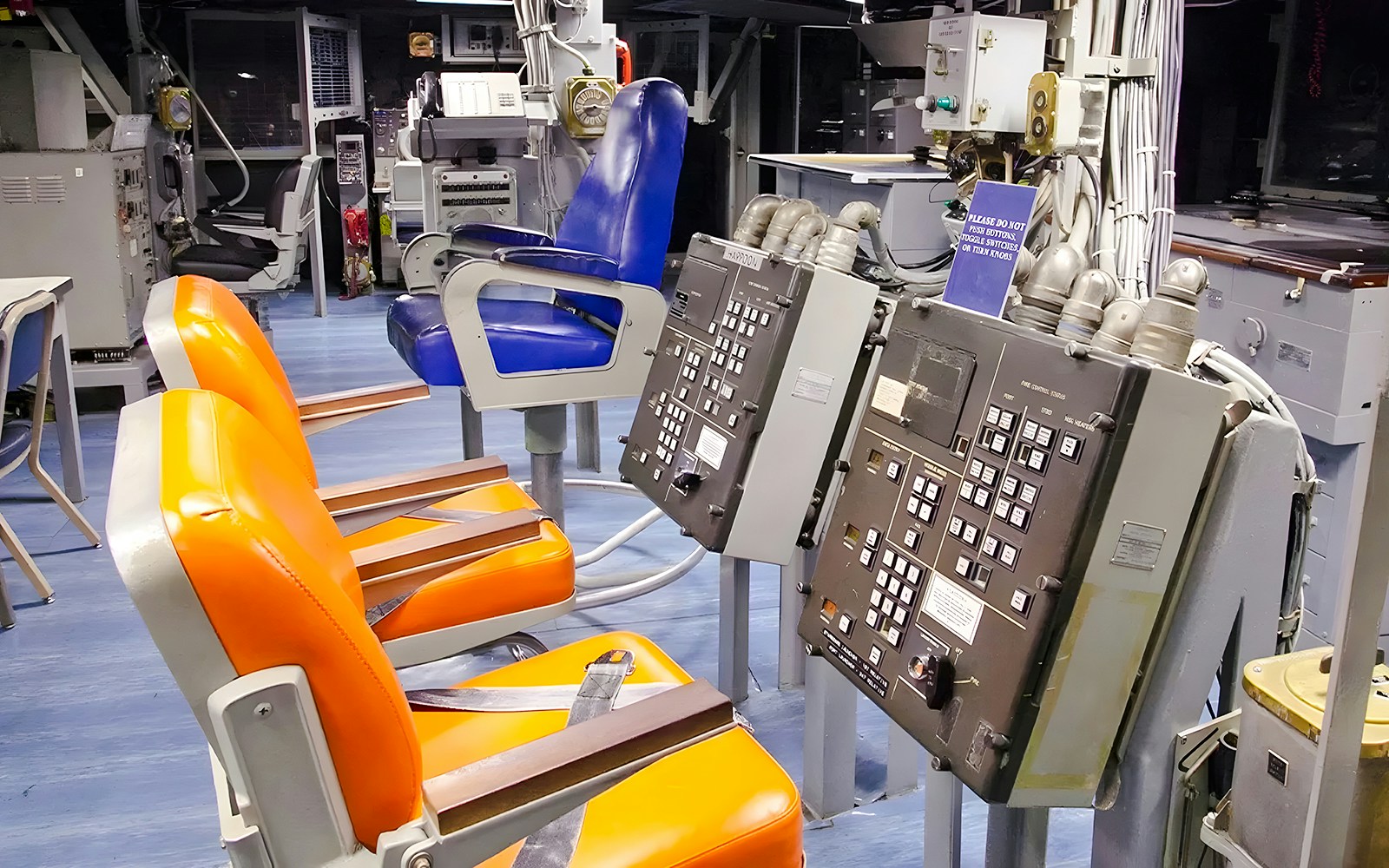 Control room inside USS Missouri with orange and blue chairs and control panels.