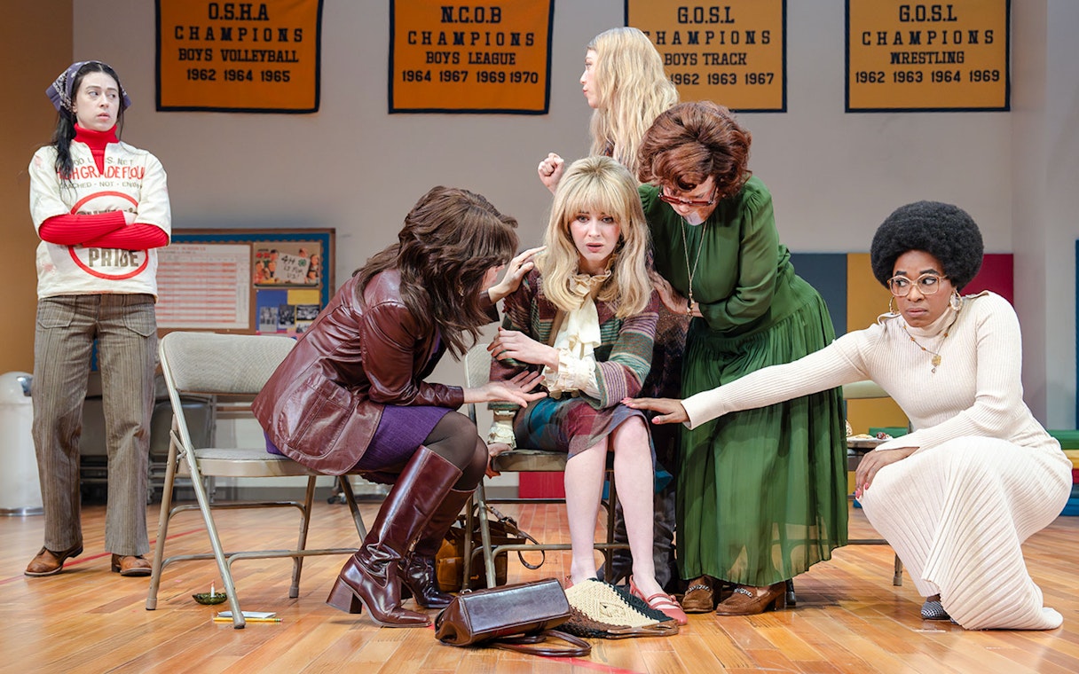 Women in a scene from the Liberation Broadway show, with championship banners in the background.