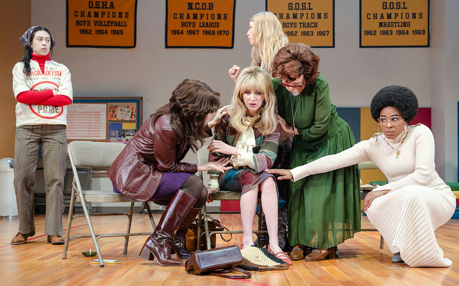 Women in a scene from the Liberation Broadway show, with championship banners in the background.