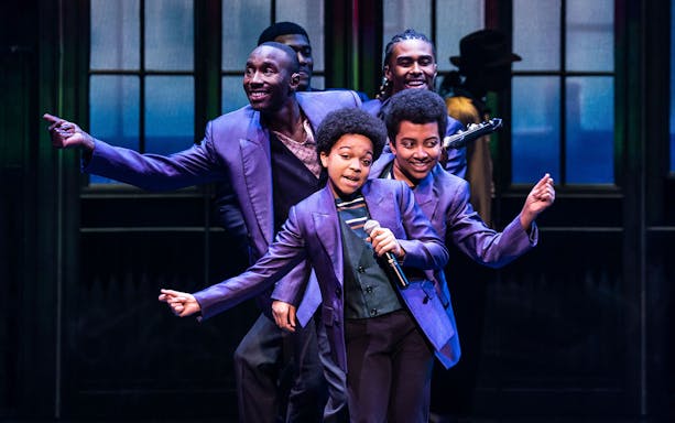 Performers in purple suits dancing on stage during MJ Das Musical.