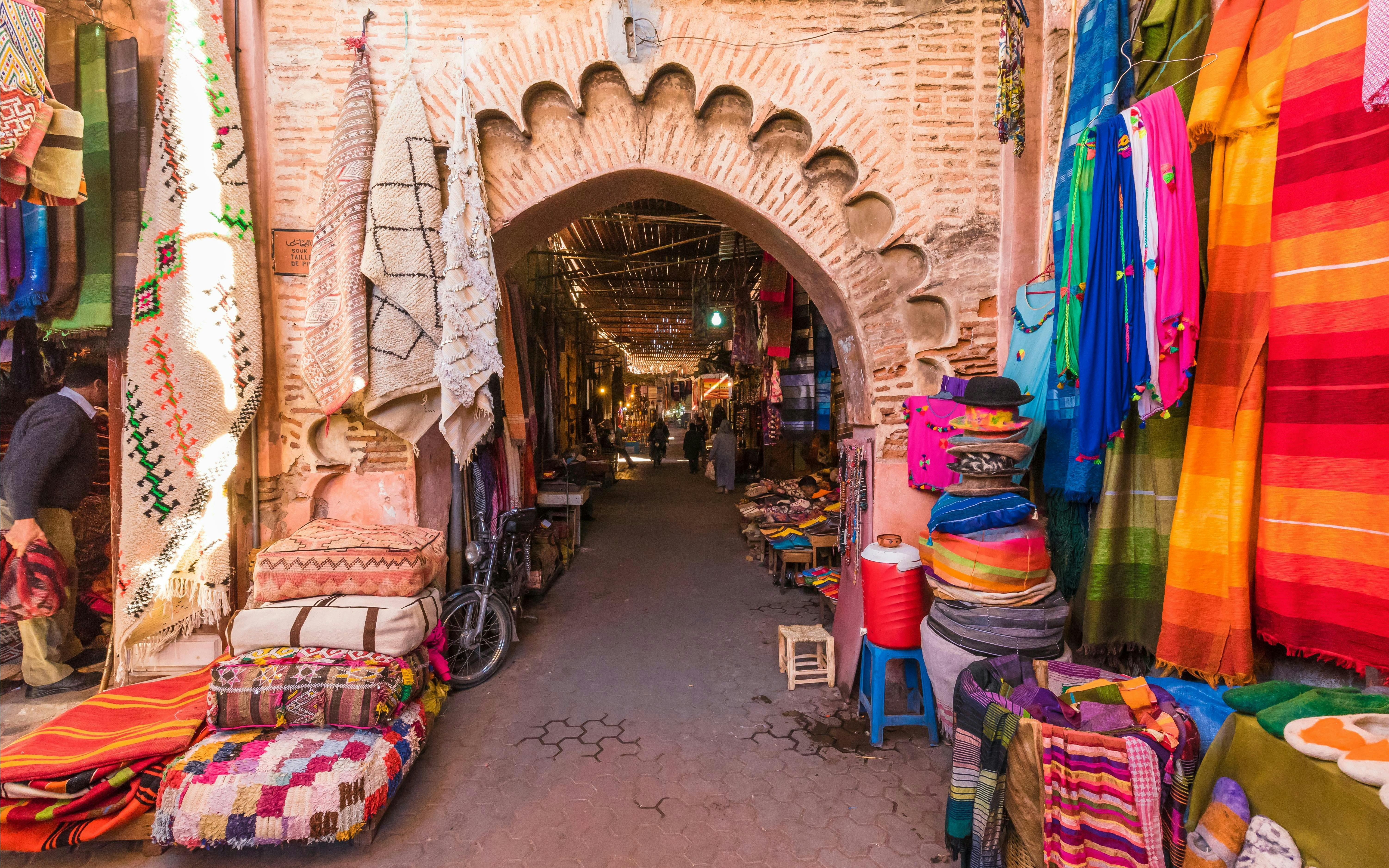 Souvenirs and textiles displayed at Jamaa el Fna market in Marrakesh, Morocco.