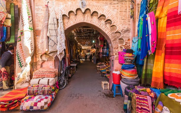 Souvenirs and textiles displayed at Jamaa el Fna market in Marrakesh, Morocco.