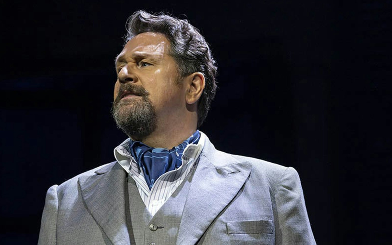 Man in a suit and scarf performing in "Aspects of Love" stage production.