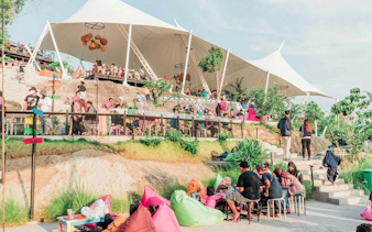 Outdoor seating area with people relaxing under a large canopy in Dubai.