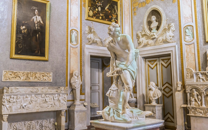 Bernini's David sculpture in Borghese Museum, Rome, surrounded by classical art.