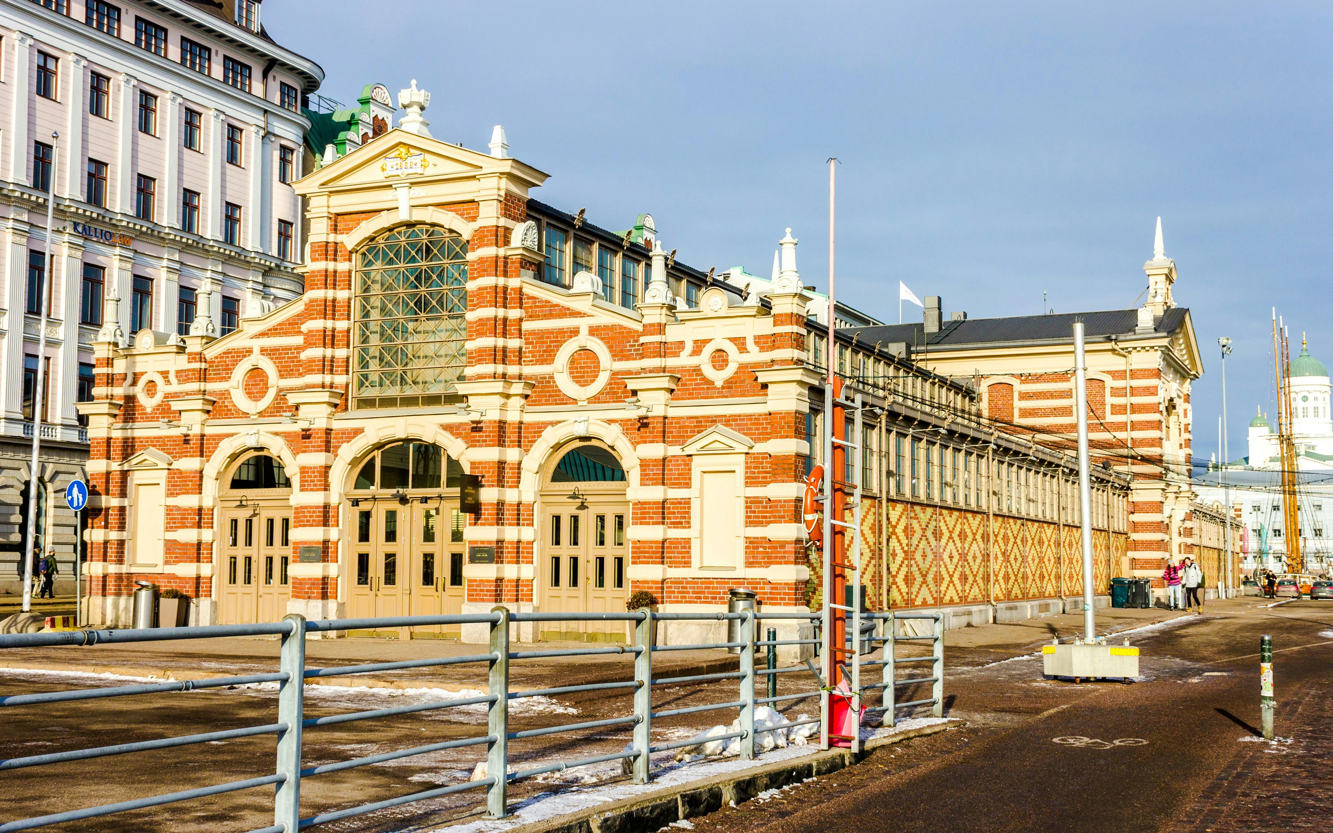 Antigo Mercado Municipal de Helsínquia, com fachada de tijolo vermelho e janelas em arco.