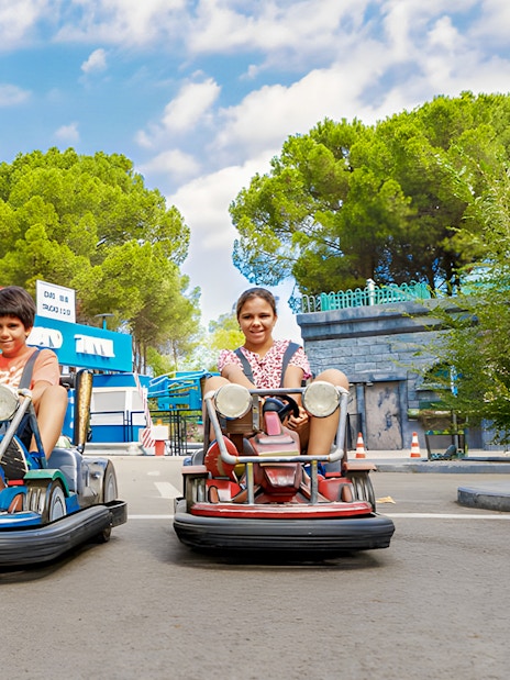 Children driving bumper cars at Parque de Atracciones de Madrid with TMNT theme.