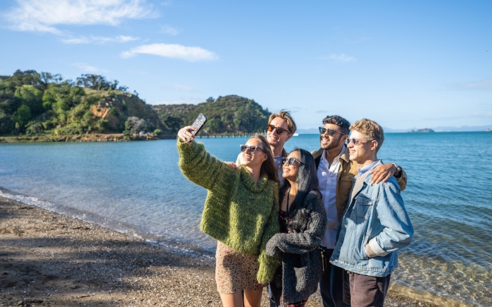 Tour group taking a selfie on the beach at Waiheke Island, New Zealand.