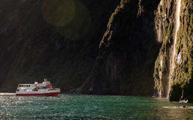 Cruise boat near waterfall in Milford Sound, New Zealand.