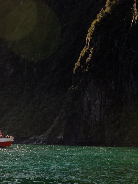 Cruise boat near waterfall in Milford Sound, New Zealand.
