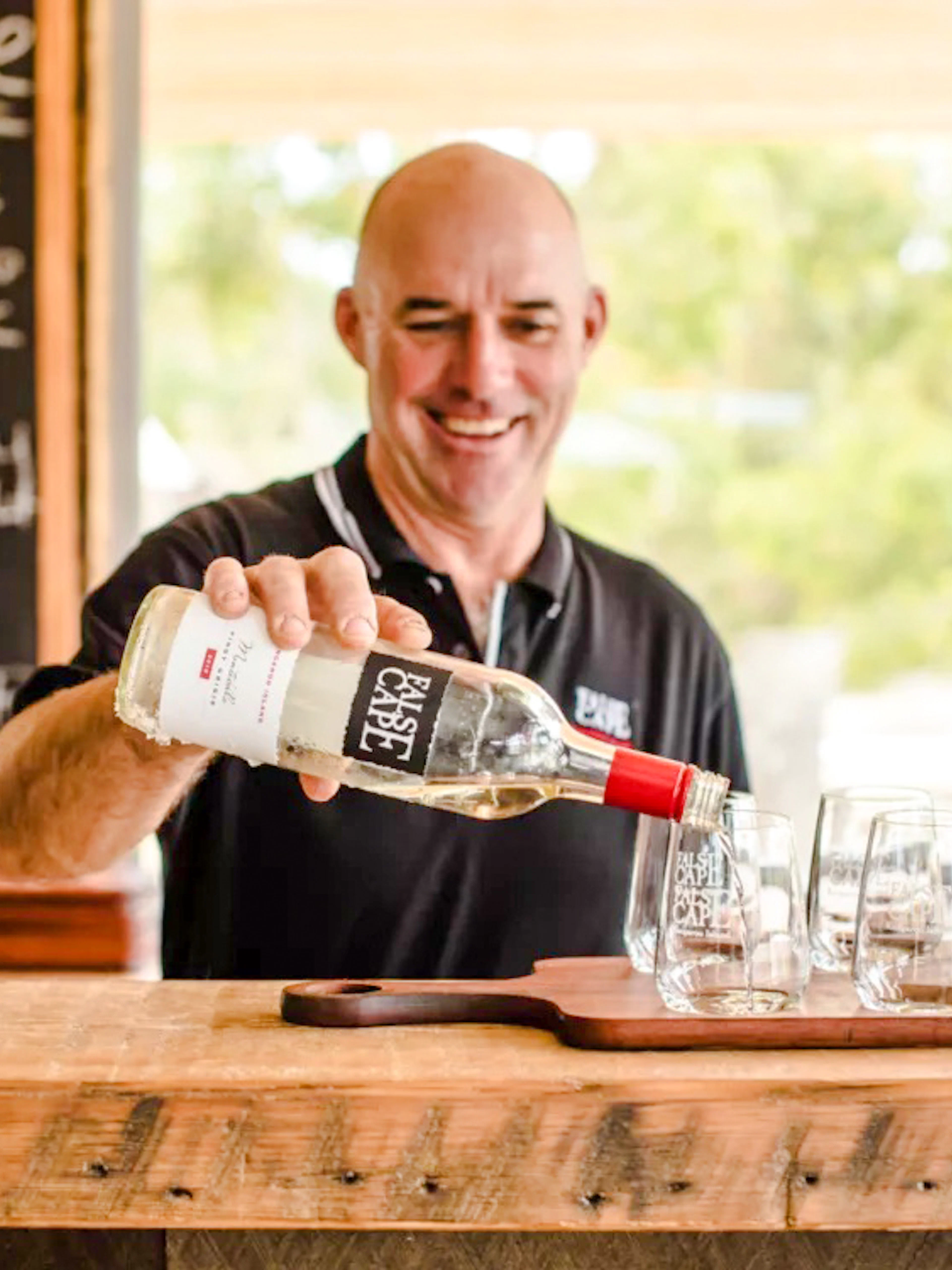 Man pouring wine into glass at False Cape, Kangaroo Island.