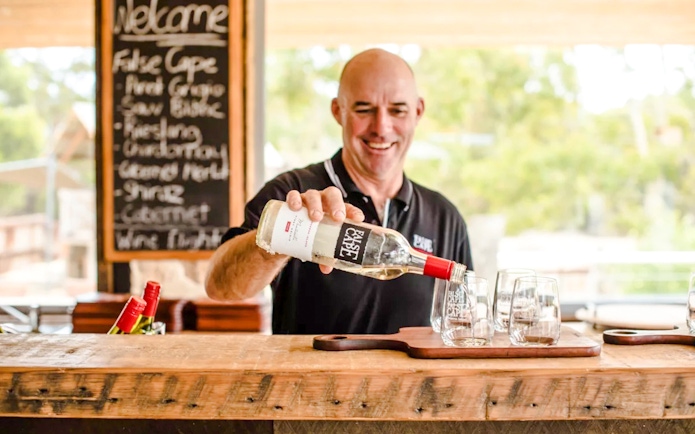 Man pouring wine into glass at False Cape, Kangaroo Island.