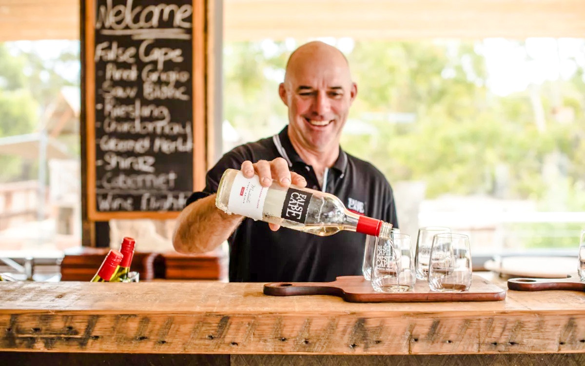 Man pouring wine into glass at False Cape, Kangaroo Island.