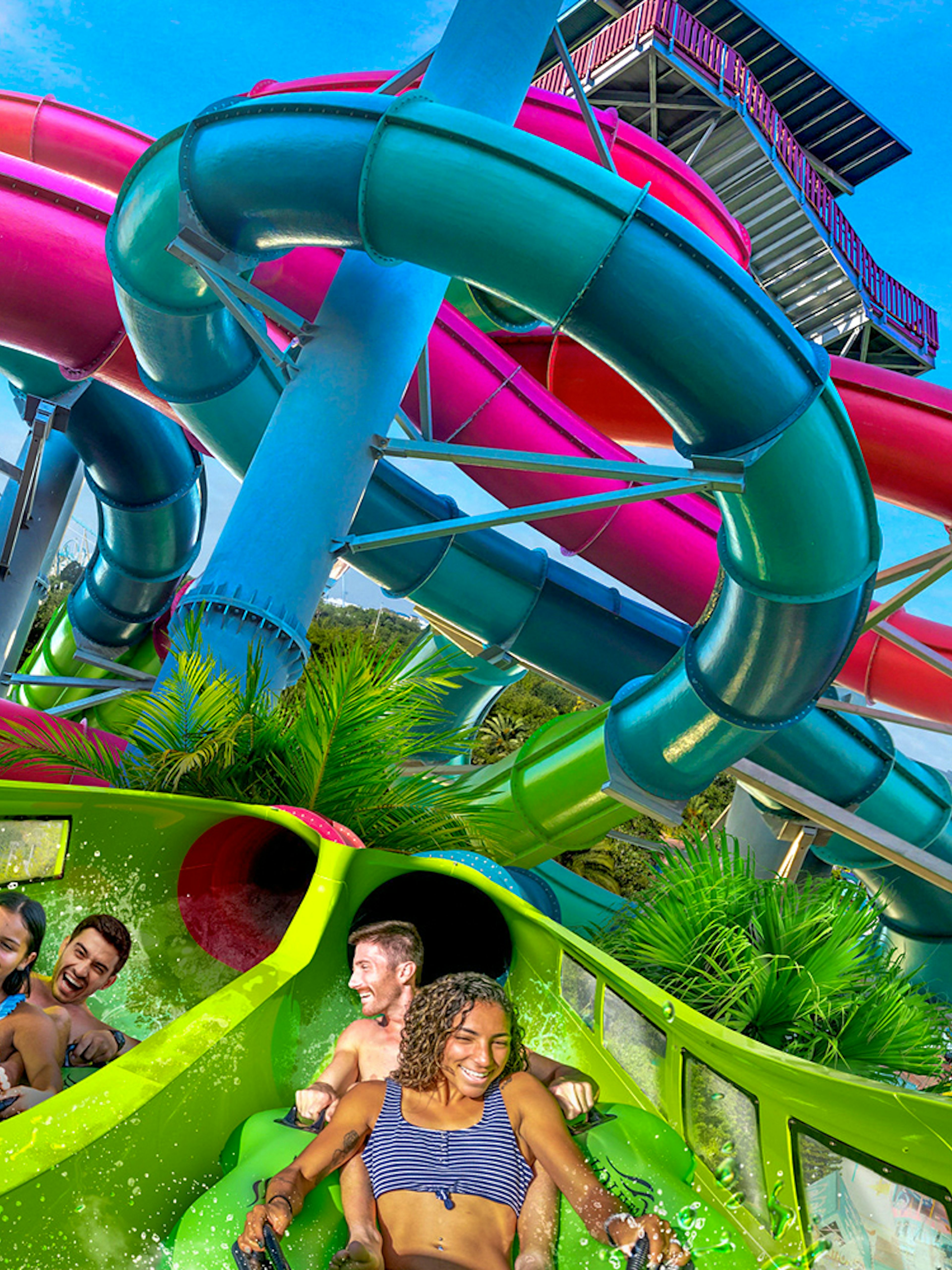Visitors enjoying a water slide at Aquatica Orlando with colorful tubes in the background.