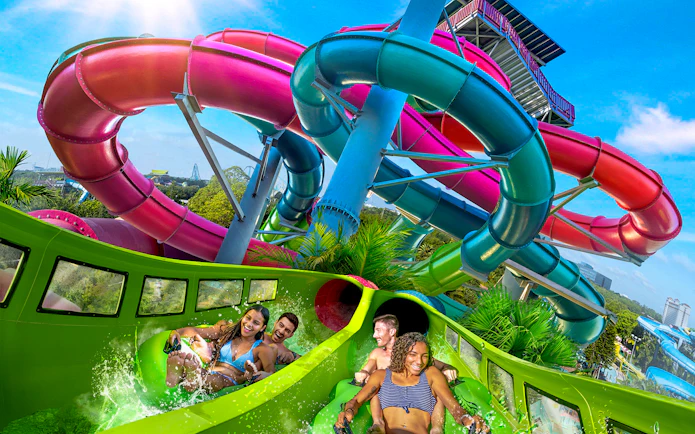 Visitors enjoying a water slide at Aquatica Orlando with colorful tubes in the background.