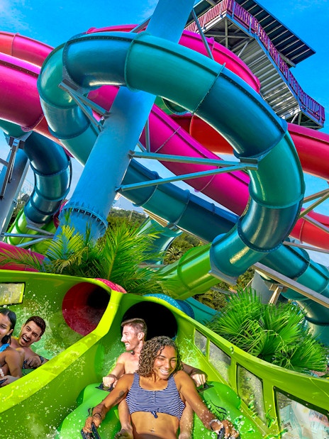 Visitors enjoying a water slide at Aquatica Orlando with colorful tubes in the background.