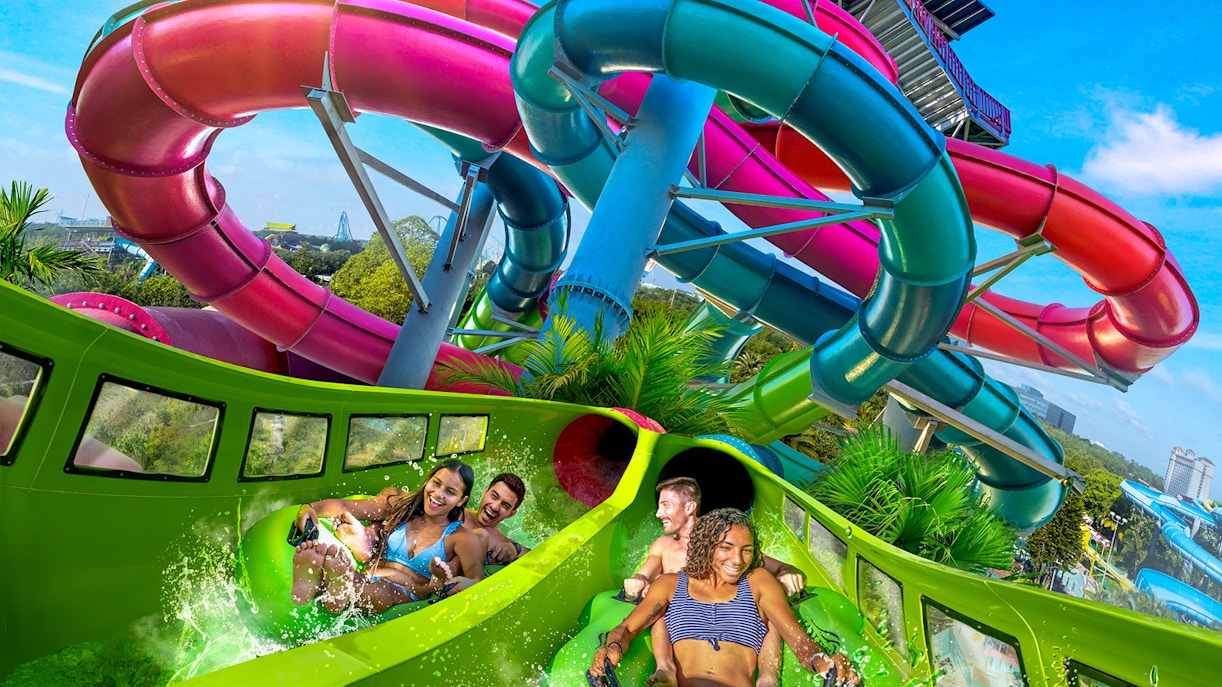 Visitors enjoying a water slide at Aquatica Orlando with colorful tubes in the background.