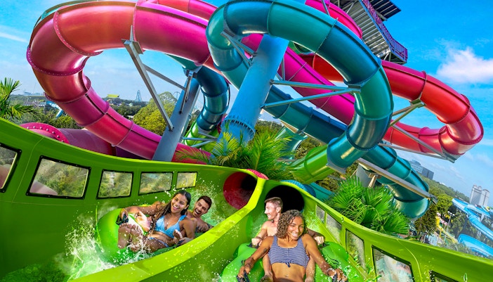 Visitors enjoying a water slide at Aquatica Orlando with colorful tubes in the background.