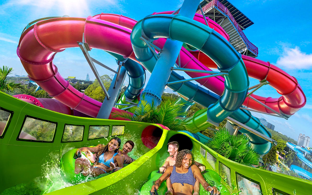 Visitors enjoying a water slide at Aquatica Orlando with colorful tubes in the background.